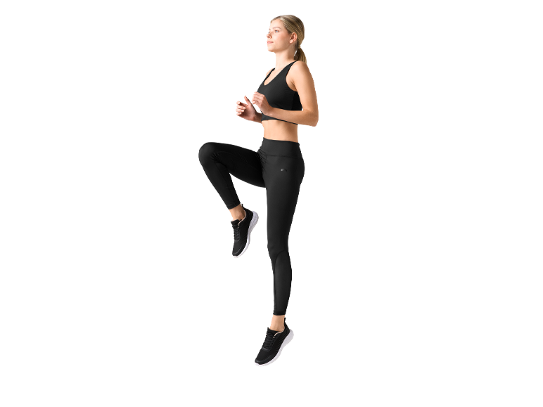 Donna in top sportivo e leggings neri, che si allena.