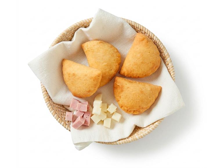 Quattro empanadas fritte con cubetti di prosciutto e formaggio in un cesto di vimini.