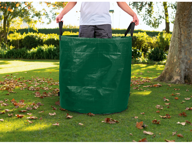 Sacco da giardino verde con manici, pieno di foglie, in un giardino soleggiato.