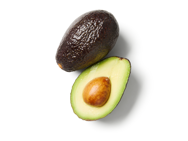 Avocado intero e tagliato a metà con nocciolo su sfondo bianco.