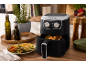 Friggitrice ad aria con verdure arrostite, bottiglie d'olio e spezie in cucina.