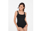 Donna con canotta nera con pizzo e slip neri, sorridente.