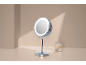 Specchio da trucco illuminato e bastoncini di cotone su sfondo beige.