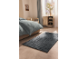 Camera da letto con letto, tappeto blu e mobile in legno accanto alla finestra.