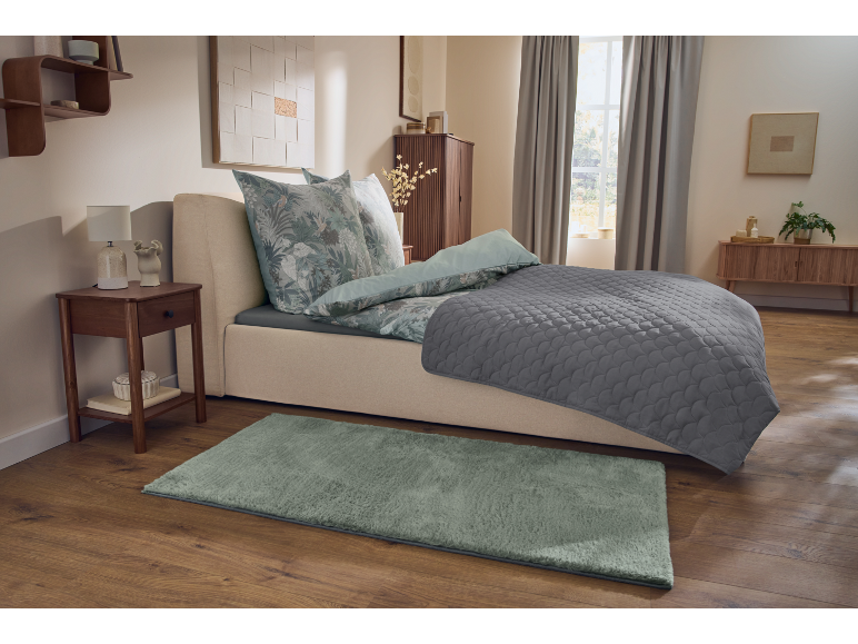 Accogliente camera da letto con letto, comodino, tappeto ed elementi decorativi.