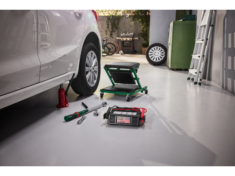 Auto su cric, con caricabatterie, chiave dinamometrica e carrello da officina.