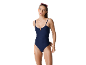 Donna in costume da bagno intero blu scuro a costine con occhiali da sole rosa sulla testa.