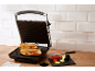 Piastra per panini con due panini grigliati e verdure fresche in cucina.
