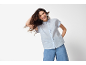 Donna con camicia di lino a righe azzurre a maniche corte e jeans larghi.