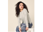 Donna con maglione grigio chiaro e jeans, seduta e che guarda altrove.