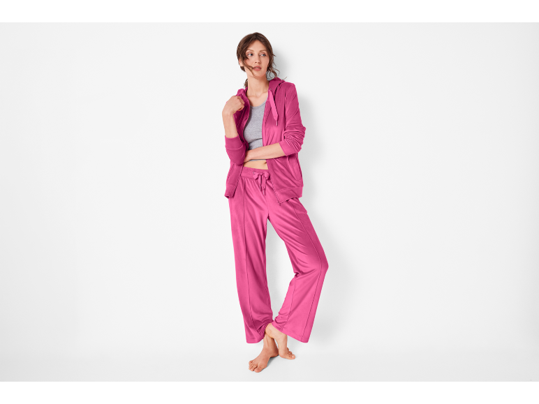 Donna in tuta fucsia, giacca con cerniera e pantaloni larghi.