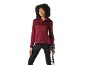 Donna con giacca con cappuccio bordeaux e leggings neri che tiene bastoncini da trekking.