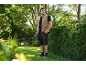 Uomo in gilet e pantaloncini che tiene un tagliasiepi in un giardino.