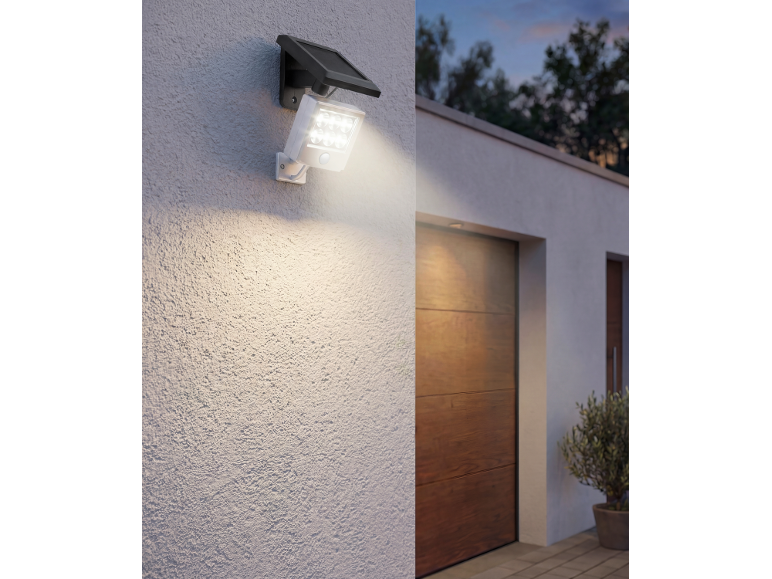 Lampada solare da esterno con sensore di movimento su una parete vicino a un garage.