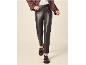 Donna con pantaloni in pelle scura, giacca marrone e mocassini con nappe