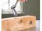 Chiave a bussola universale con cricchetto avvita una vite in un pezzo di legno.