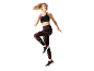 Donna con reggiseno sportivo nero e leggings stampati, che salta.