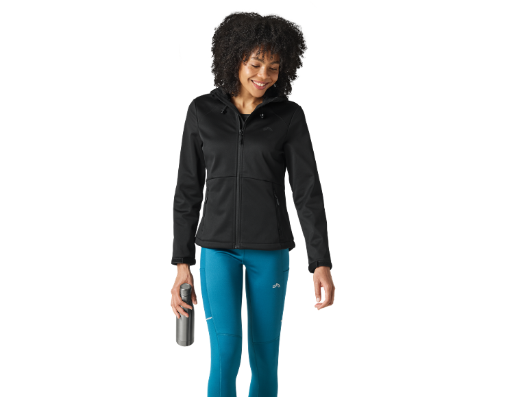 Donna in giacca nera con cappuccio e leggings blu che tiene una bottiglia d'acqua.