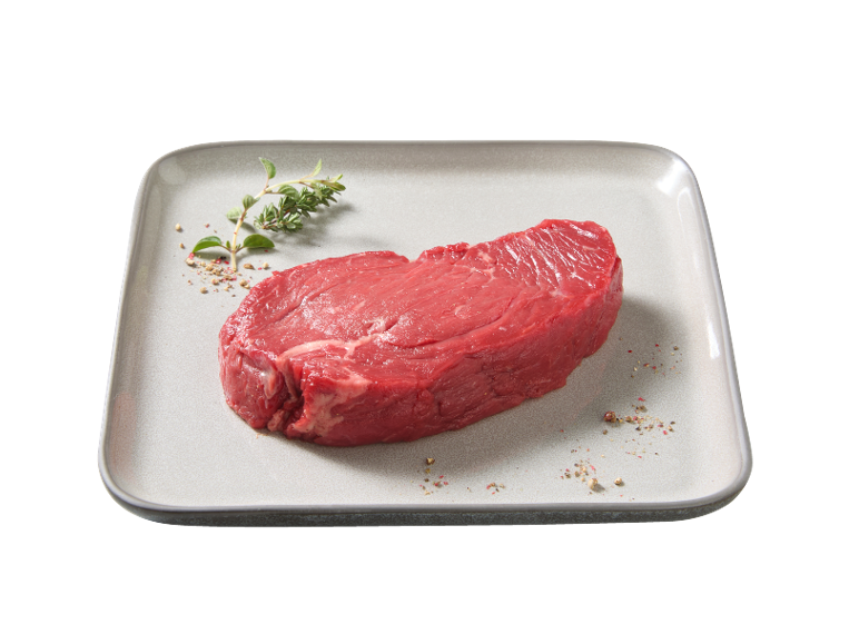 Bistecca di manzo cruda con erbe e pepe su un piatto.