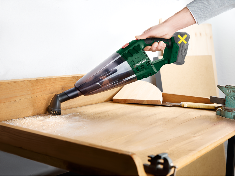 Aspirapolvere portatile che pulisce trucioli di legno da un banco da lavoro.