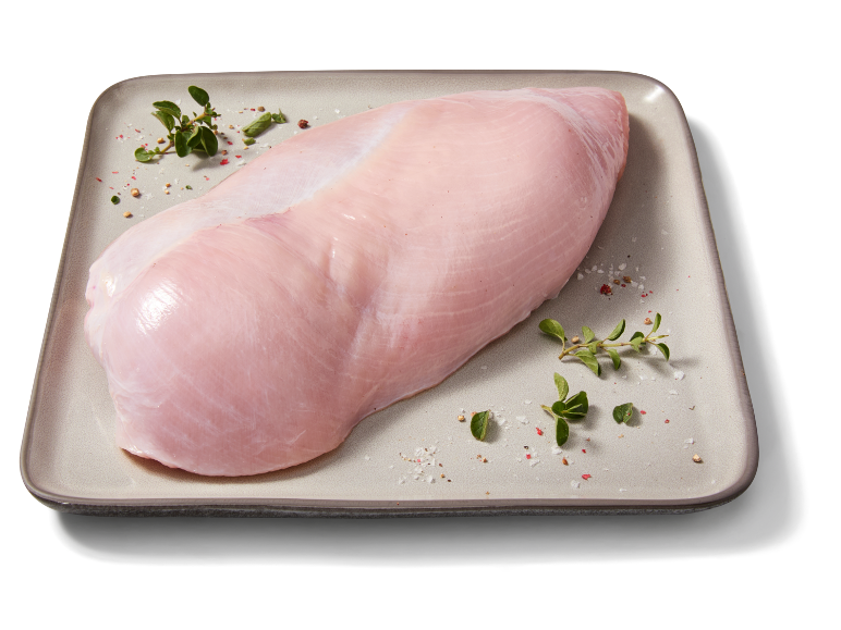 Fesa di tacchino cruda su un piatto con erbe e spezie