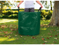 Sacco da giardino verde con manici, pieno di foglie, in un giardino soleggiato.