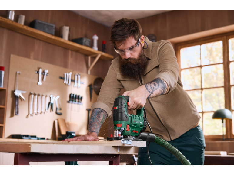 Uomo con seghetto alternativo taglia legno in officina.