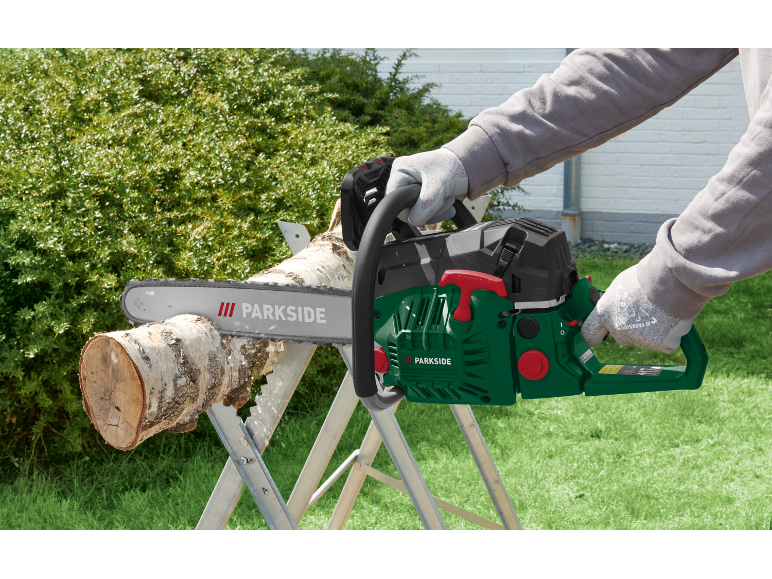 Uomo che taglia un tronco con una motosega su un cavalletto.