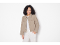 Donna sorridente con giacca beige, top e pantaloni bianchi.