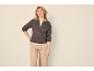 Donna con cardigan marrone, maglietta bianca e pantaloni beige.