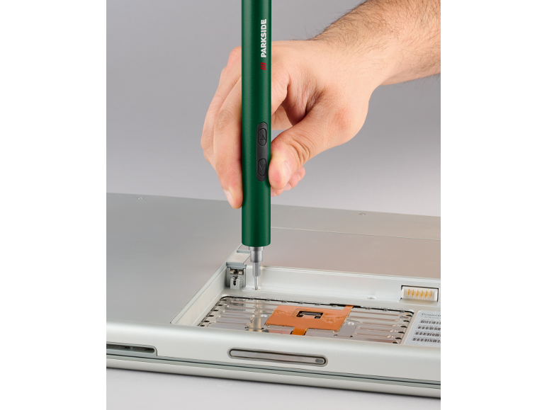 Mano che usa un cacciavite elettrico verde per riparare un laptop.