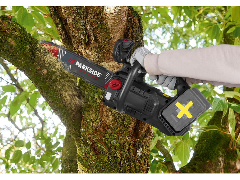 Persona che sega un ramo d'albero con una motosega a batteria.