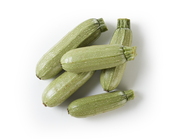 Un mucchio di zucchine verde chiaro su sfondo bianco.