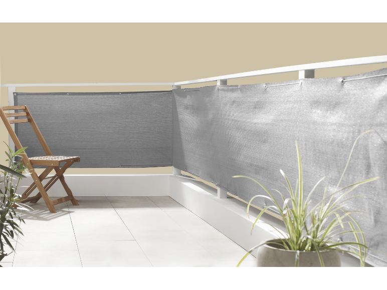 Balcone con schermo privacy grigio, sedia in legno e piante in vaso.