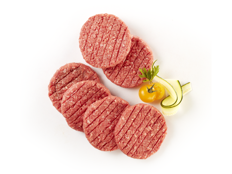 Hamburger di carne cruda con pomodoro giallo e cetriolo su sfondo bianco.
