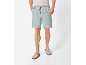 Uomo che indossa pantaloncini grigio chiaro con coulisse verde e zoccoli beige.