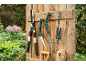 Forbici da giardino, seghe e cesoie appese a una parete di legno davanti a un giardino.