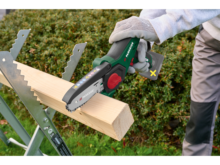 Mini motosega a batteria che taglia legno su un cavalletto.
