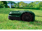 Robot tagliaerba su erba verde davanti a una casa.
