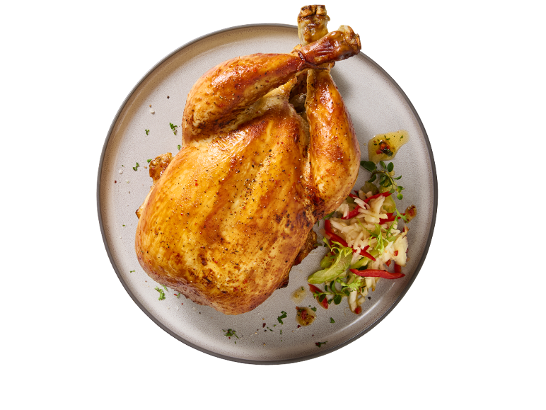 Pollo arrosto intero con erbe e insalata su un piatto.
