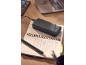 Power bank nero in carica su un quaderno aperto con una penna, un laptop sullo sfondo.
