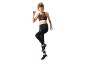 Donna con reggiseno sportivo stampato e leggings neri, che salta.
