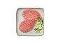 Due hamburger di carne cruda su un piatto con cetrioli, cipolla rossa e basilico.