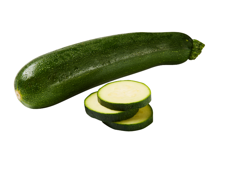 Zucchina verde intera e tre fette di zucchina su sfondo nero.