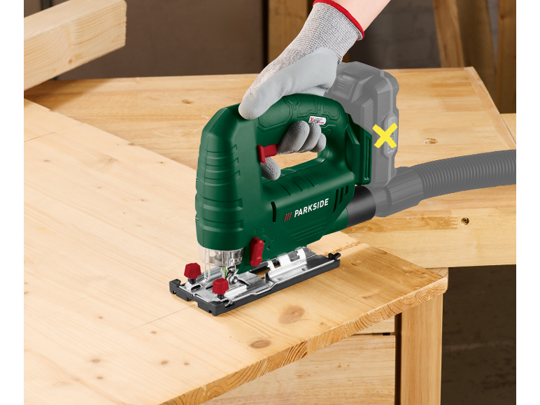 Seghetto alternativo in mano che taglia una tavola di legno, con attacco per l'aspirazione della polvere.