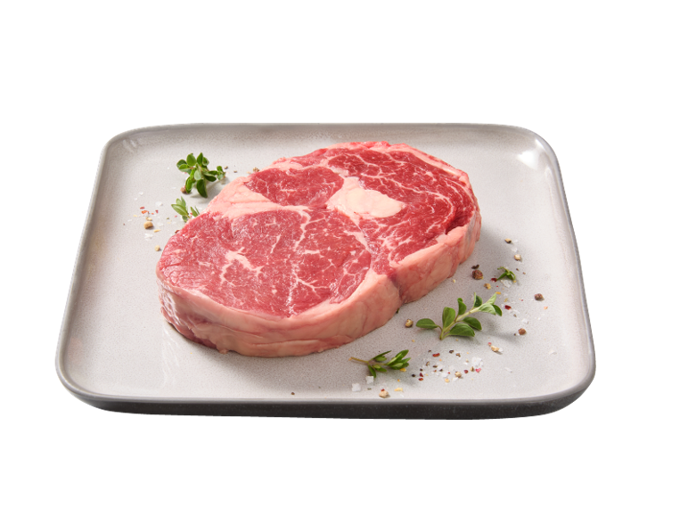 Bistecca di manzo cruda con erbe e spezie su un piatto.