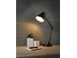 Lampada da scrivania nera illumina una scrivania in legno con un quaderno e penne in contenitori bianchi.