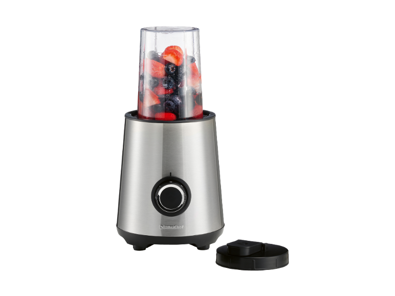 Frullatore in acciaio inossidabile con frutti di bosco nel bicchiere e coperchio accanto
