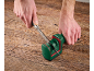 Uomo che affila un coltello con un affilacoltelli verde e rosso su un tavolo di legno.