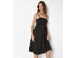 Donna in abito nero con spalline, collana e bracciale dorati.